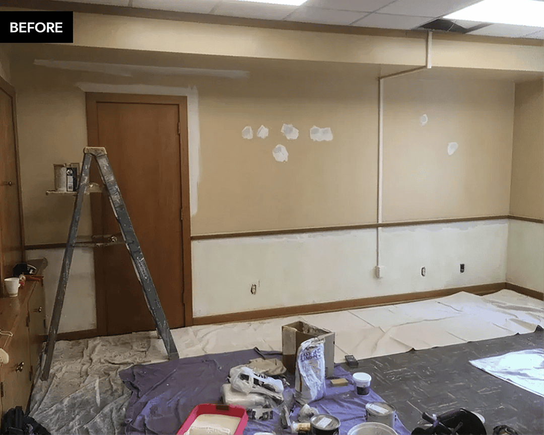Office interior pre-renovation with painting supplies.